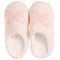 A pair of fluffy off-white slip-on slippers with a light pink bow design embellished with small white pearls on the top, shown against a plain white background.