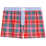 A pair of boxer shorts featuring a vibrant red, pink, and green plaid pattern on the body, a light blue and white striped waistband, and a three-button front closure.