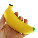 Hand holding a banana squishy stress item on a white background