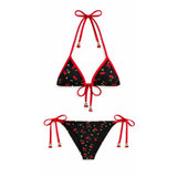 Black bikini set with red accents and floral pattern on a white background