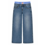 A pair of wide-leg blue denim jeans with a light blue elastic waistband and a small red embroidered logo patch at the front center.