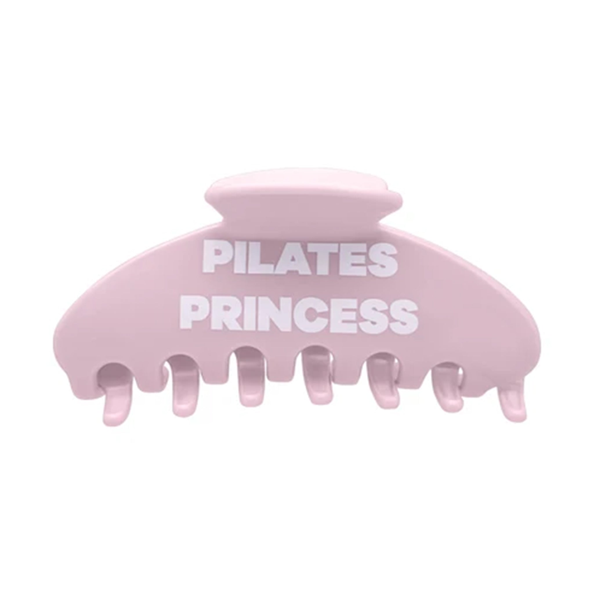 A light pink hair claw clip with the words 'PILATES PRINCESS' printed in bold white capital letters across the front, set against a plain white background.