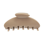 A single hair claw clip in a warm beige or cream color, photographed from a top-down angle on a solid white background.