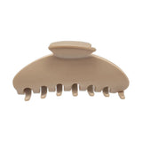 A single hair claw clip in a warm beige or cream color, photographed from a top-down angle on a solid white background.