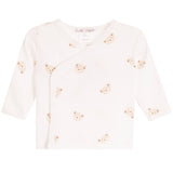 A baby long-sleeve wrap top in off-white, decorated with a pattern of small beige teddy bear faces. The top features an asymmetrical snap closure and is displayed flat against a solid white background.