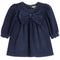 A toddler girl's navy blue denim long-sleeve top featuring a large matching fabric bow at the neckline and ruffled cuffs, shown against a plain white background.