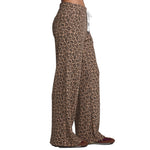 Side view of a person wearing leopard-print wide-leg pants with a white drawstring, paired with brown shoes, against a plain white background.
