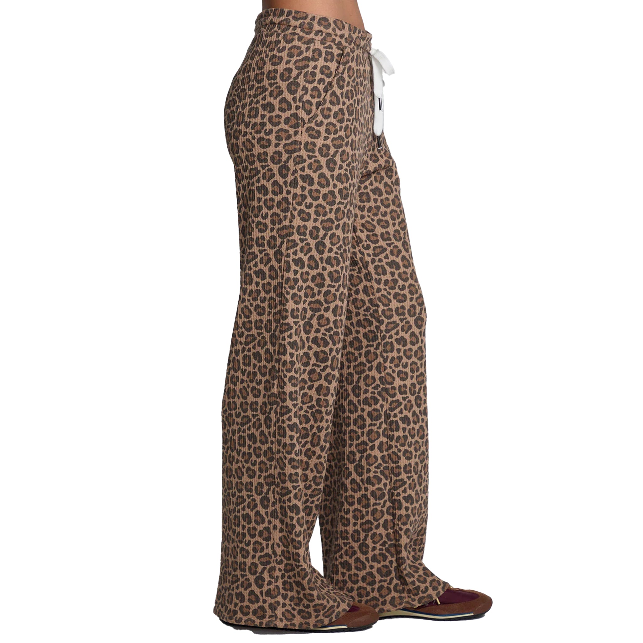 Side view of a person wearing leopard-print wide-leg pants with a white drawstring, paired with brown shoes, against a plain white background.