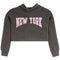 A dark heather gray cropped hoodie sweatshirt featuring the words 'NEW YORK' printed in arched pink varsity-style letters with a white outline across the chest, displayed on a solid white background.