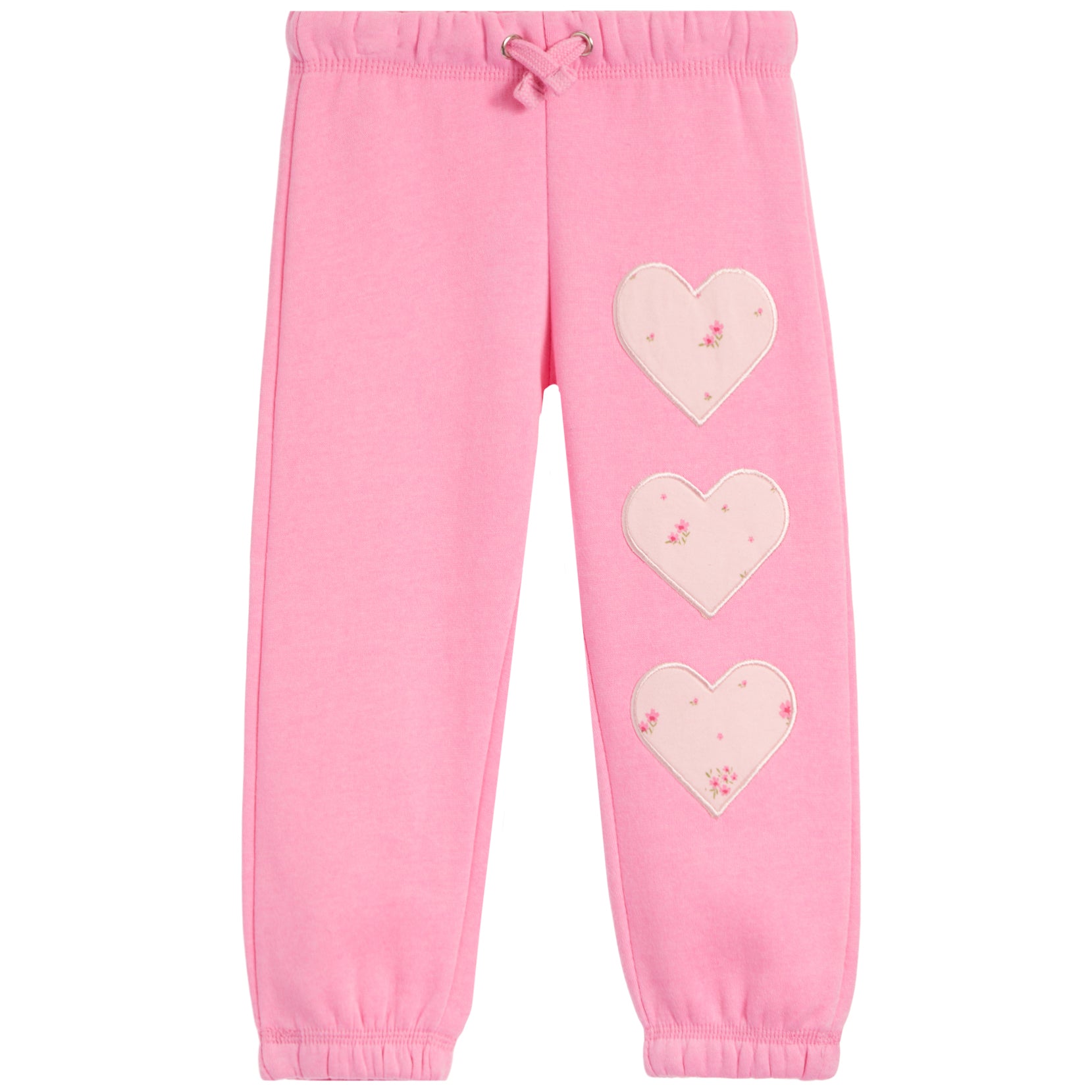 Pink sweatpants with three light pink heart patches decorated with tiny floral details, arranged vertically on the left leg. The pants feature an elastic waistband with a matching drawstring and elastic cuffs at the ankles.