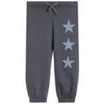 Dark gray jogger pants with three light blue denim star patches arranged vertically on the left leg, featuring an elastic waistband with a drawstring and elastic cuffs.