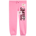 Pink jogger pants with a drawstring waist, elastic cuffs, and graphic patches on the left leg featuring the word 'SMILE' in black, the number '22', a bow illustration, and a cherry graphic.