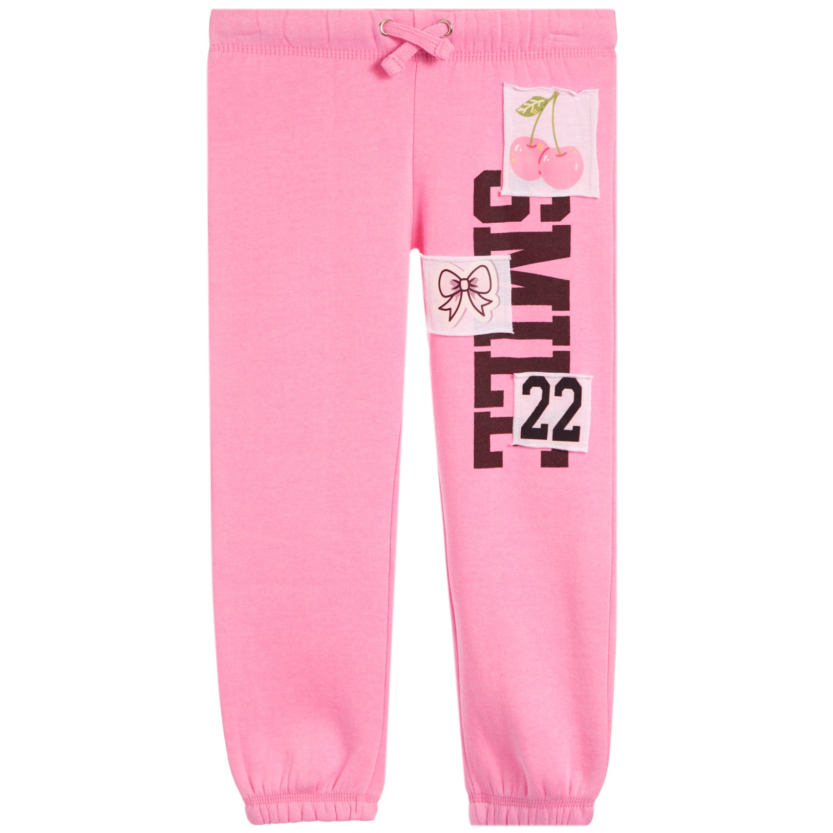 Pink jogger pants with a drawstring waist, elastic cuffs, and graphic patches on the left leg featuring the word 'SMILE' in black, the number '22', a bow illustration, and a cherry graphic.