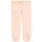 Light peach pink sweatpants with a subtle tonal bow pattern printed down the left leg, featuring an elastic waistband with a drawstring and elastic cuffs.
