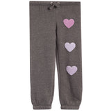 A pair of dark gray heather jogger pants featuring three textured, chenille lavender-pink hearts running down the right leg, with a matching gray heather drawstring waistband.