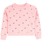 A light pink long-sleeve crewneck sweatshirt for toddlers, featuring an all-over pattern of small black bows, shown flat on a white background.