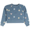A dusty blue cropped sweatshirt with an all-over print of smiley faces, hearts, and simple smiley faces in pink, white, and yellow.