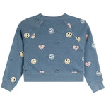 A kids' long-sleeve crewneck sweatshirt in heathered dusty blue, decorated with an all-over pattern of smiley faces, hearts, and bows in pastel colors, shown flat on a white background.