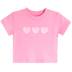 A pink short-sleeve baby t-shirt with three light pink hearts printed across the chest, displayed on a solid white background.