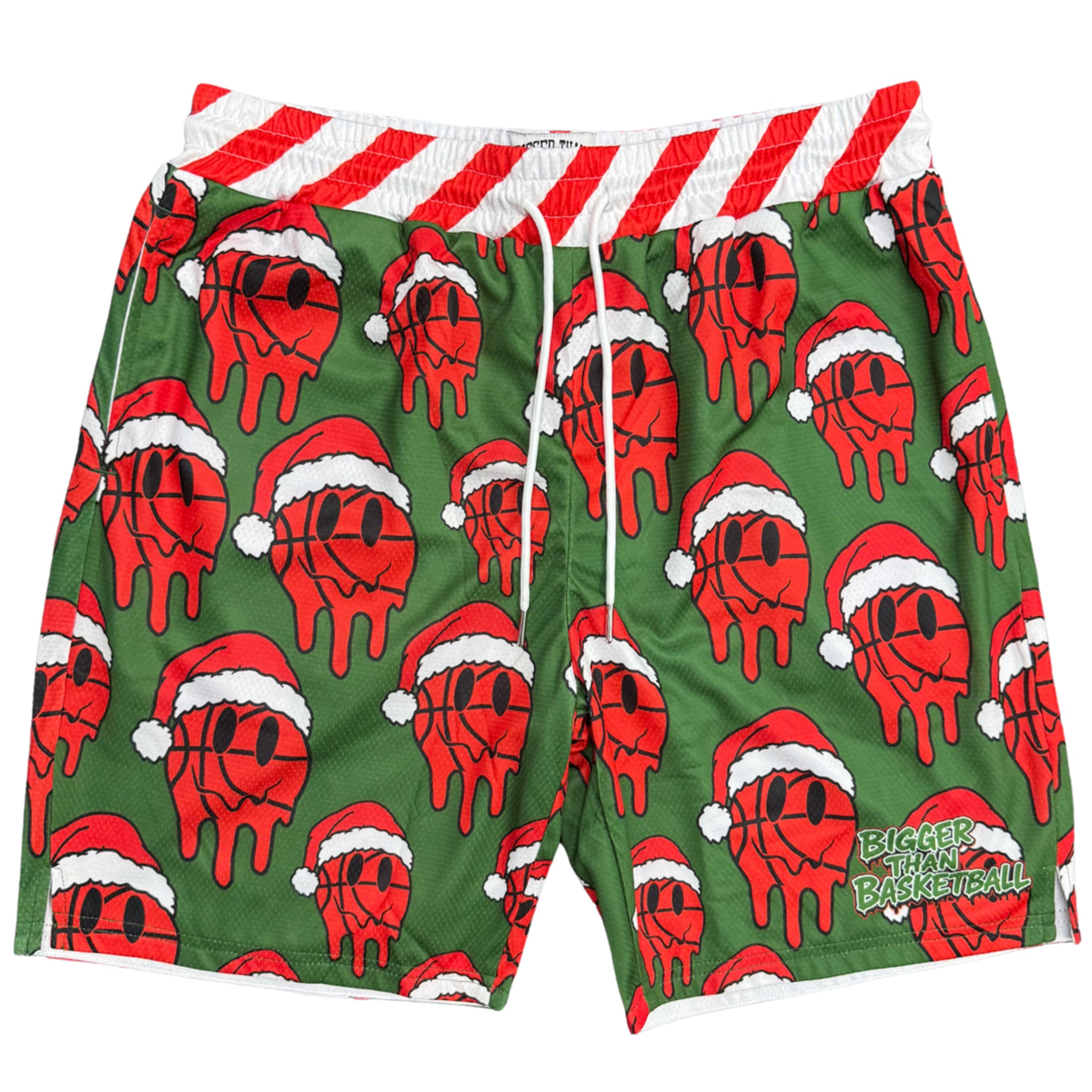Green swim trunks with an all-over red basketball wearing a Santa hat pattern, a red and white striped waistband, and white drawstrings. A green 'Bigger Than Basketball' logo is printed on the lower right leg.