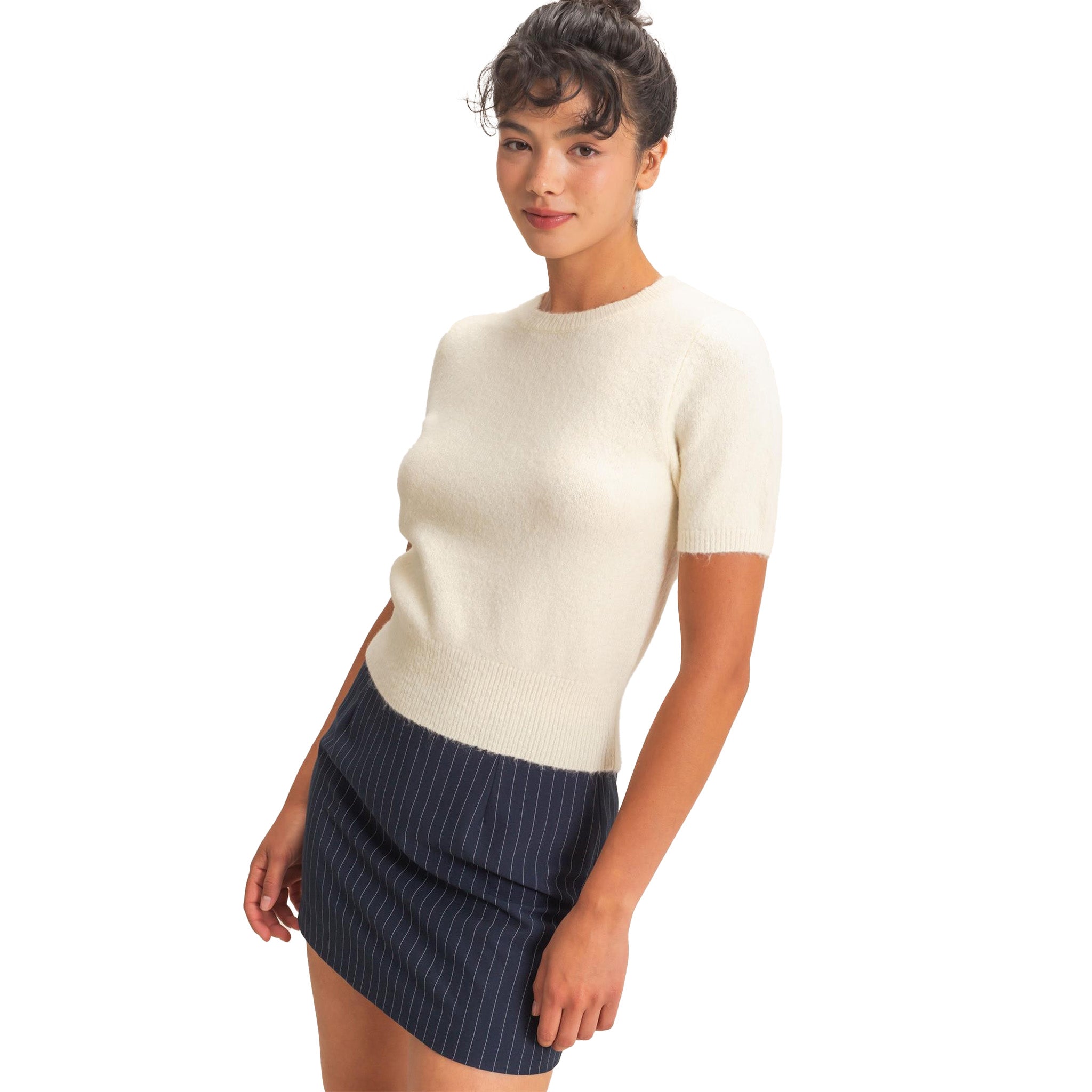 A woman modeling a short-sleeve cream knit sweater set against a plain white background.