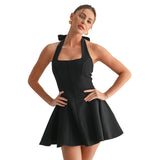 A woman modeling a black halter-neck mini dress with a structured corset-style bodice and flared skirt, posed against a plain white studio background.