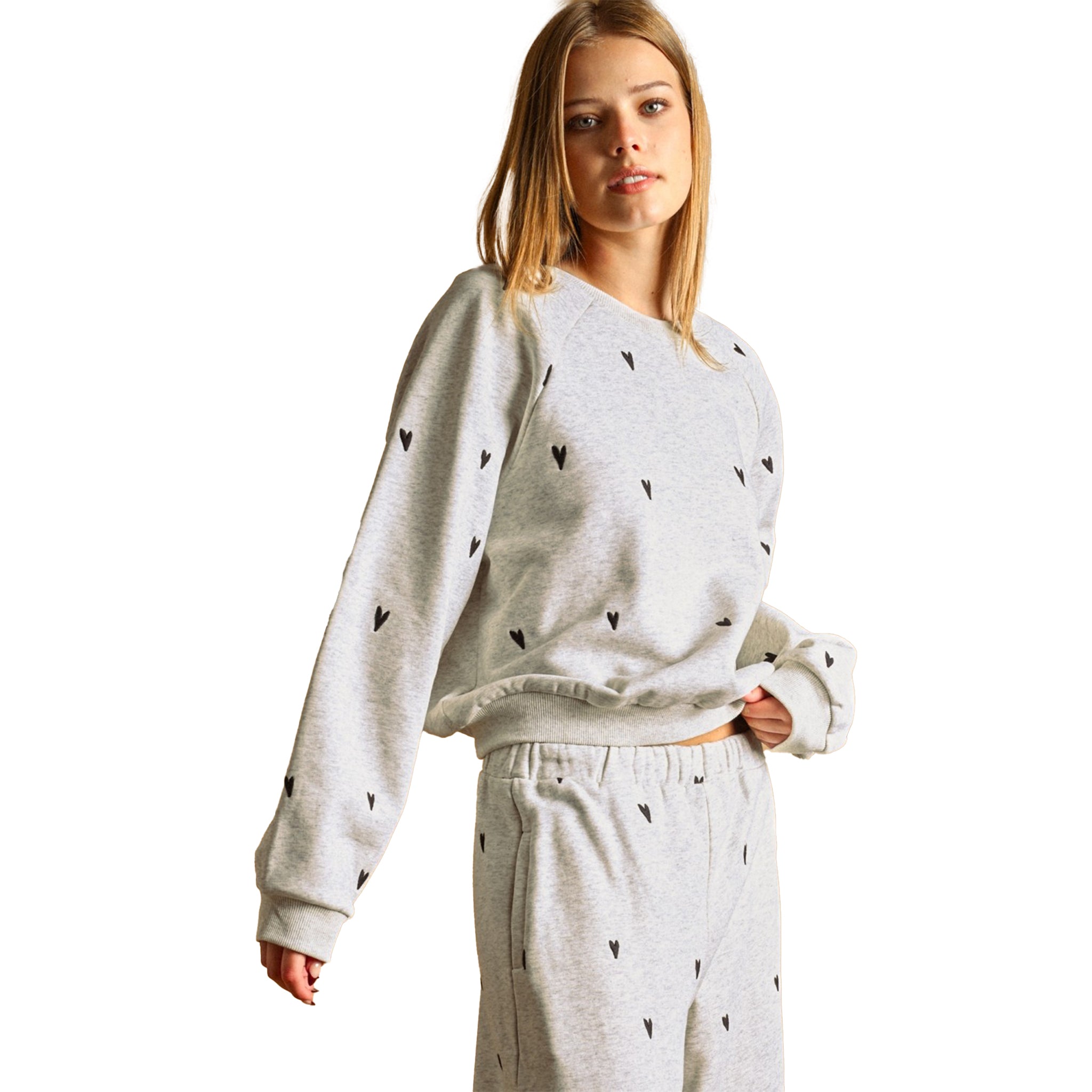 A woman modeling a light gray heather sweatshirt featuring a small black heart pattern, against a solid white background.