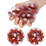 A hand squeezes a clear, basketball-shaped stress ball filled with small red and black basketballs. Two round clear containers filled with more of the same basketball-filled stress balls are shown below on a white background.