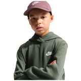 A child wearing a dark olive green Nike hoodie with a white logo on the chest, paired with a dusty rose Nike cap, set against a plain white background.