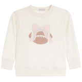 An off-white long-sleeve crewneck sweatshirt featuring a graphic of a brown football with white laces and a light pink bow on the front.