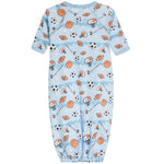 A baby long-sleeve footless onesie in light blue, featuring an all-over sports-themed print with basketballs, soccer balls, footballs, and referees on a white background.
