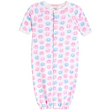 A baby long-sleeve footless sleeper with an all-over pink and blue smiley face pattern, featuring a snap-button front closure and elastic cuffs.