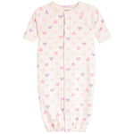 A baby sleep sack in cream with an all-over pattern of small pink and purple hearts, featuring short raglan sleeves and a front snap closure.