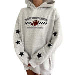 A light heather gray hoodie with a black and white football graphic on the chest reading 'Friday Night Lights Football America,' plus black star patches on the sleeves, shown on a cropped model against a white background.