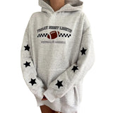 A light heather gray hoodie with a black and white football graphic on the chest reading 'Friday Night Lights Football America,' plus black star patches on the sleeves, shown on a cropped model against a white background.