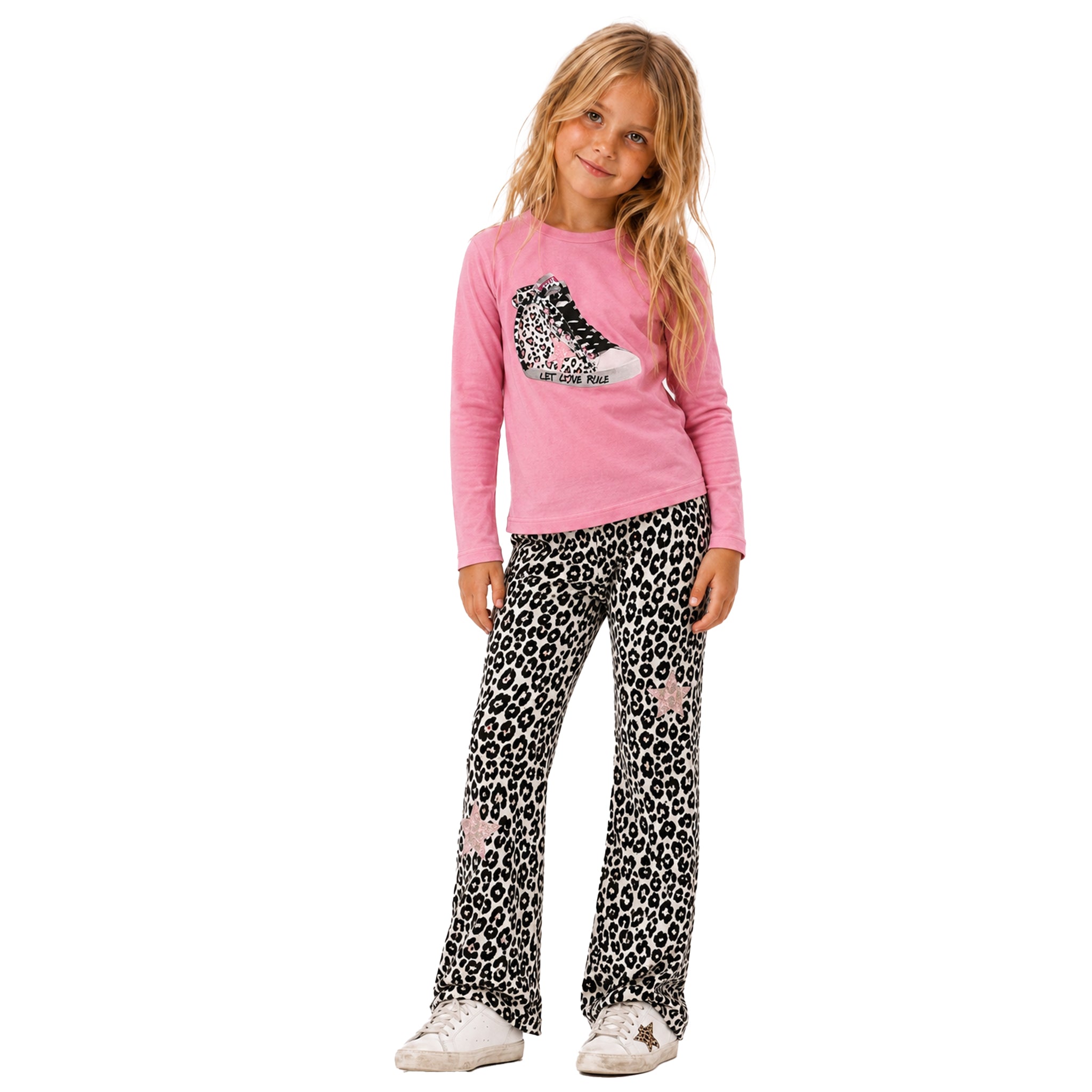 A young girl modeling a two-piece set consisting of a pink long-sleeve top with a sequined sneaker graphic and black-and-white leopard print pants with pink star details, paired with white sneakers, on a solid white background.