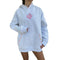 A person wearing an oversized light grey heather hoodie with a pink flower graphic on the chest, multicolored dotted trim along the hood and pockets, and a front kangaroo pocket, shown against a plain white background.