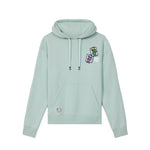 A light mint green pullover hoodie with white drawstrings, featuring a small colorful graphic on the left chest and a circular patch on the front pocket, displayed against a solid white background.