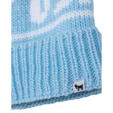 Close-up of a light blue and white knit beanie hat, showing the ribbed cuff with a small black goat logo patch.