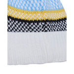Close-up of a knitted beanie hat showing horizontal color bands: light blue, yellow, black-and-white patterned, and white ribbed knit.