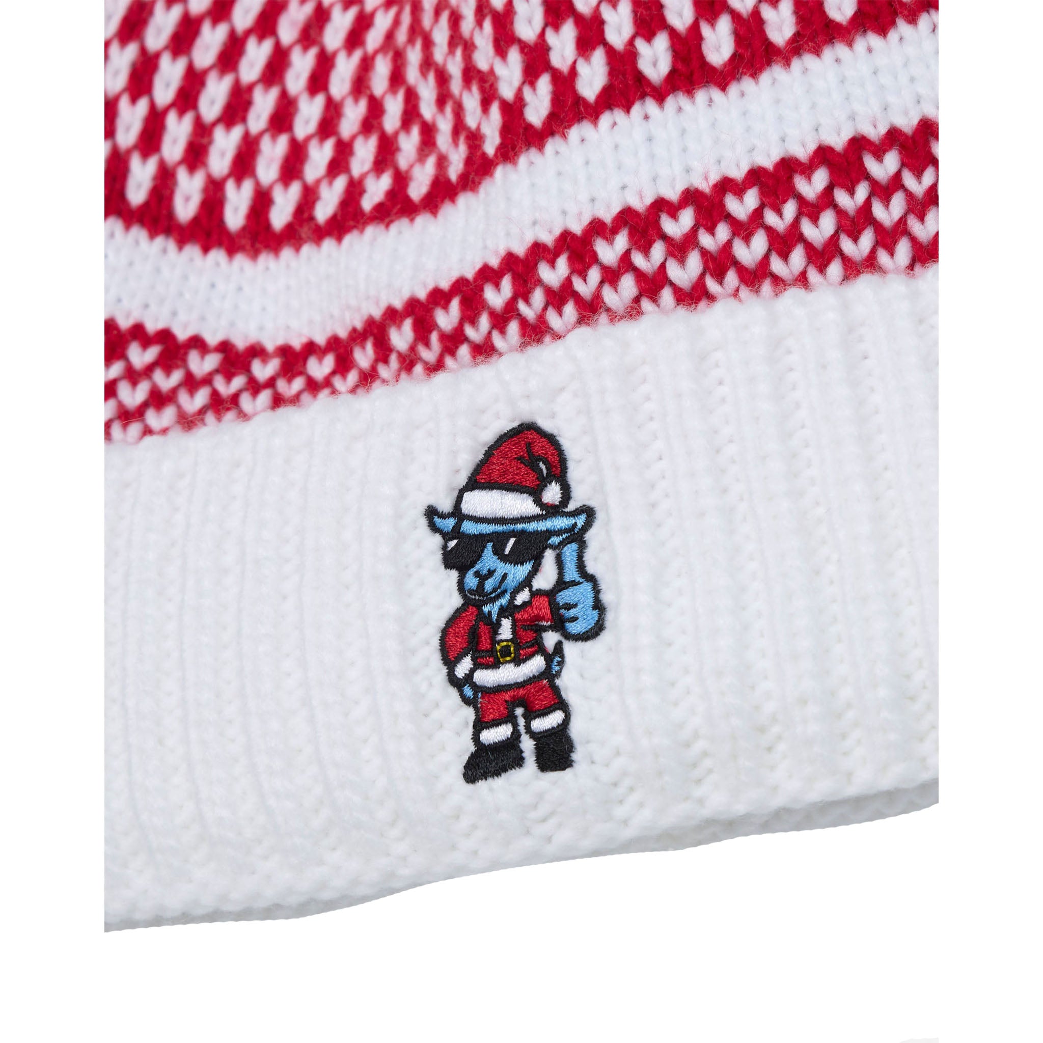 Close-up of a white knit beanie with red and white patterned stripes near the top and a small goat embroidered cartoon character wearing a Santa hat on the lower cuff.