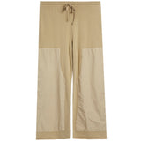 A pair of beige pants with a solid upper section and contrasting light beige patch pockets on the lower legs, featuring a drawstring waistband, shown against a plain white background.