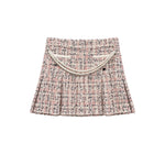 A pleated tweed mini skirt in a pink, beige, and black bouclé pattern, featuring a decorative cream-colored faux-pearl curved belt detail across the waistband, shown against a plain white background.