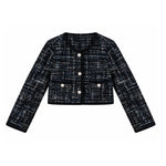 A cropped tweed jacket with long sleeves, featuring a black and white textured weave, a round neckline, three silver-tone buttons, and two front flap pockets with decorative buttons.