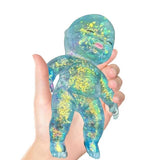 Hand holding a teal and gold baby squishy jelly toy with a white background