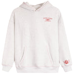 A light heather gray pullover hoodie with pink contrast stitching, featuring a red 'SUNKISSED COCONUT' graphic on the left chest and a red hibiscus flower graphic on the right sleeve cuff.