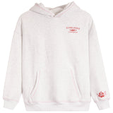 A light heather gray pullover hoodie with pink contrast stitching, featuring a red 'SUNKISSED COCONUT' graphic on the left chest and a red hibiscus flower graphic on the right sleeve cuff.