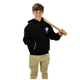 A young boy modeling a black hoodie with a small purple ice cream cone graphic on the left chest, paired with khaki pants and holding a wooden baseball bat over his shoulder against a white background.