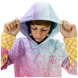 A child wearing a pastel gradient hoodie with a sprinkle pattern, holding up the hood. The hoodie features a light blue and pink gradient with white and pink sprinkles, and yellow grid-patterned sleeves.