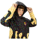 A child wearing a hooded jacket with a black background covered in multicolored sprinkles, yellow diamond-patterned cuffs and lower sleeves, and a small pink-and-yellow chest graphic, posed against a plain white background.